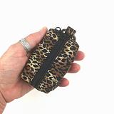 hand holding small dog waste bag dispenser in leopard print